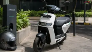 Ather's Battery Chemistry Changes illustrated with an Ather Rizta electric scooter parked beside an EV charging station in an urban setting.