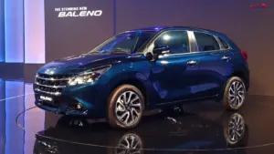 2026 Maruti Baleno facelift in dark blue displayed on a showroom stage