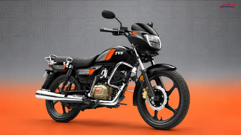 Black TVS Radeon motorcycle with orange accents, chrome details and alloy wheels against a grey and orange studio background.
