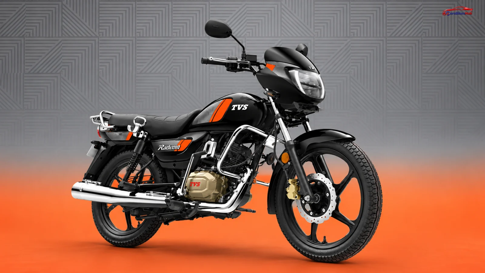 Black TVS Radeon motorcycle with orange accents, chrome details and alloy wheels against a grey and orange studio background.