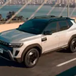 Renault Duster Hybrid in silver driving across a cable-stayed bridge, showcasing its bold front grille and rugged SUV design.